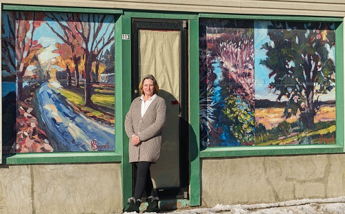 Artist standing with store front work