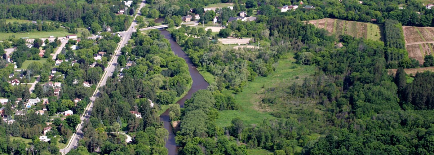 river flowing through suburban neighbourhood with lush green trees and open space