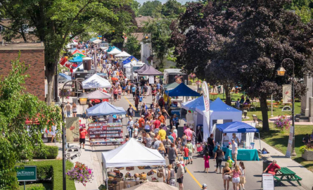 A street event. The street is lined with people, tents & different booths