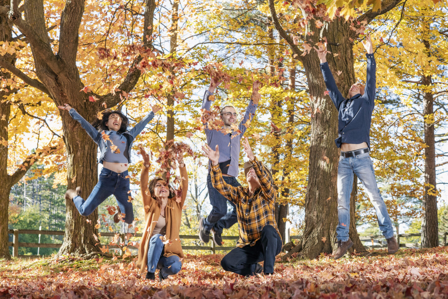 A group of people playing in fall leaves