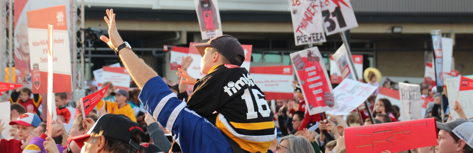 dad holding son on his shoulders in crowd of hockey fans