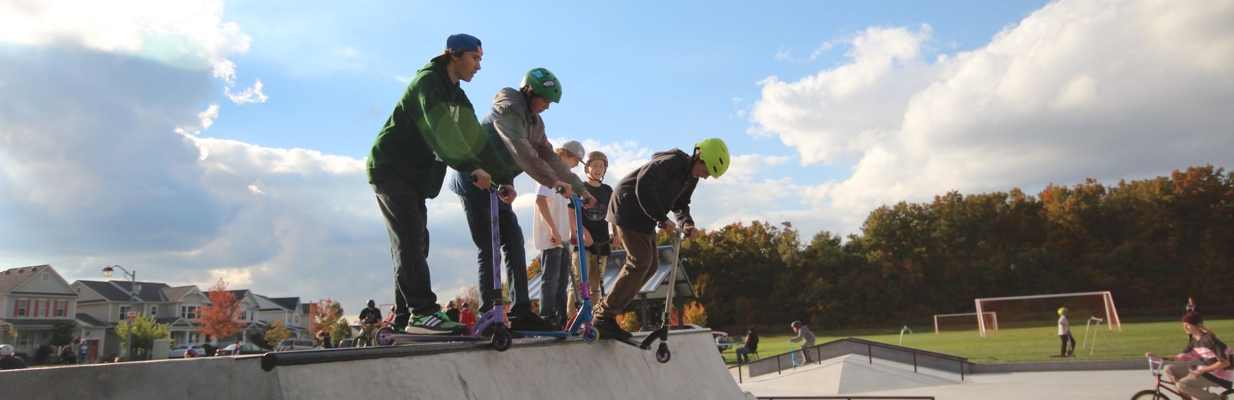 children on scooters at the top of the half pipe