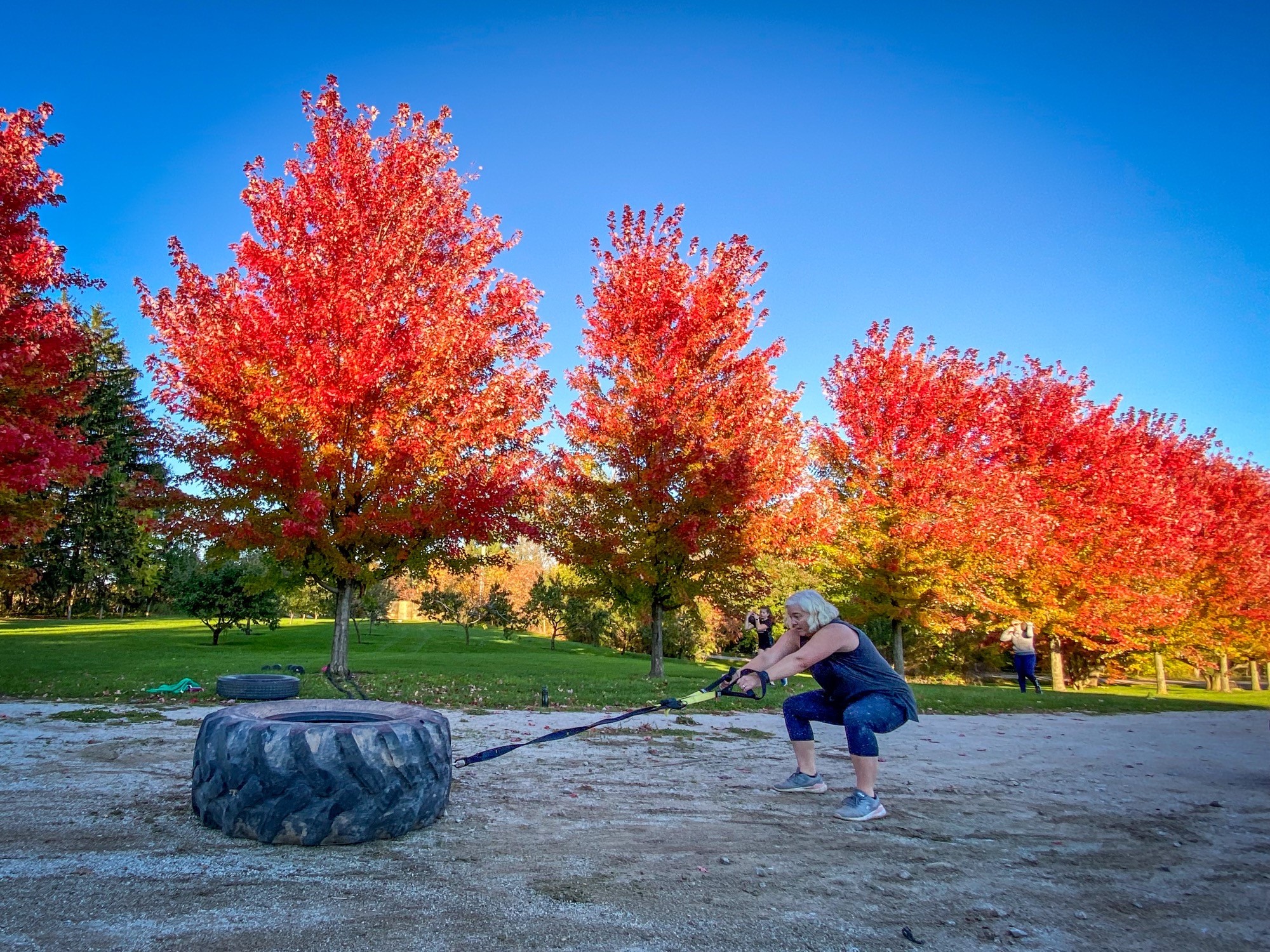 Woman pulling tire with fall leaves in background