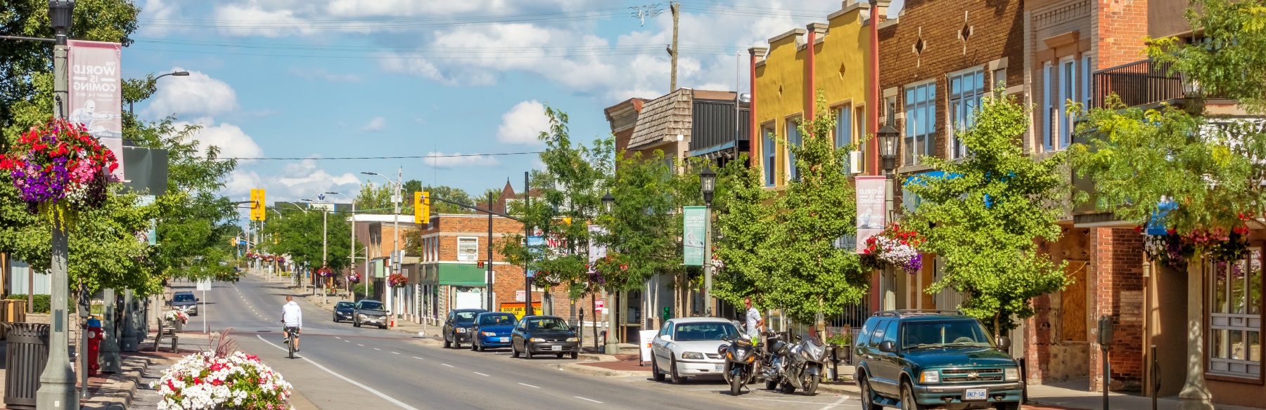 landscape of a small town with cars and people walking