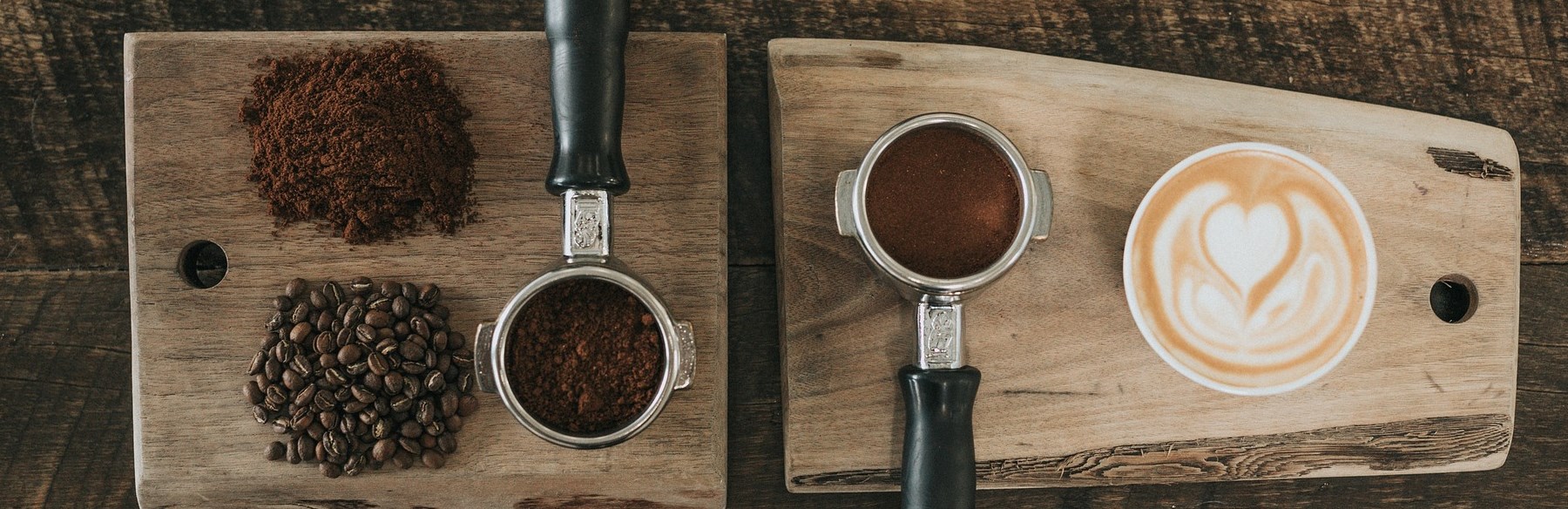 Wooden board with coffee beans, coffee grounds, and a cup of coffee