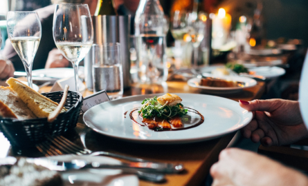 A plate with food on it surround by glasses of wine